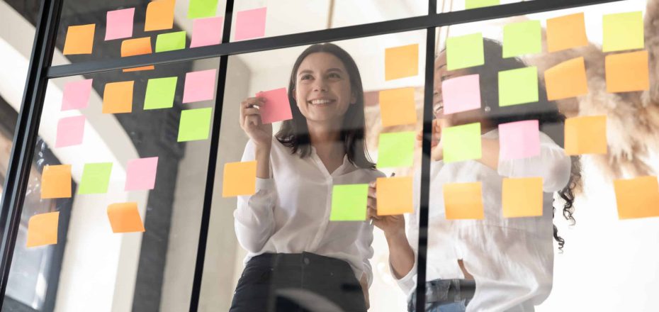 Two,Smiling,Diverse,Businesswomen,Planning,Project,On,Papers,,Adding,Colorful